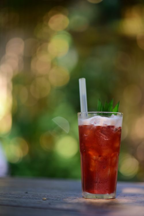 Free Chilled berry beverage with ice and straw on a wooden table outdoors. Stock Photo
