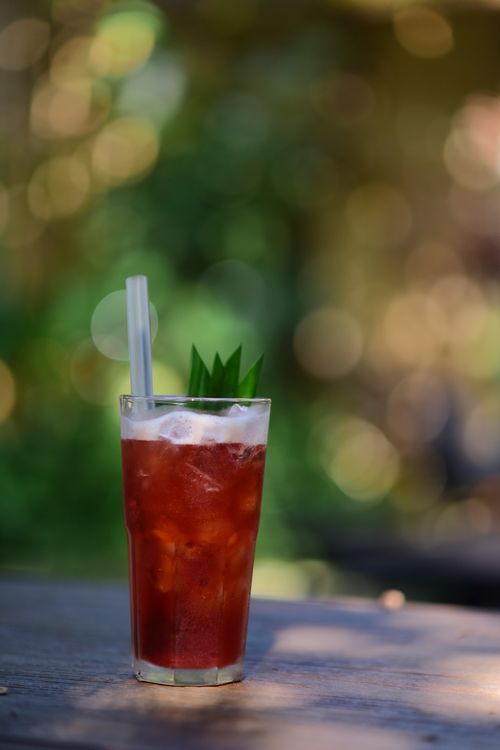 Free Chilled iced tea with ice on an outdoor wooden table, with a fresh green garnish. Stock Photo