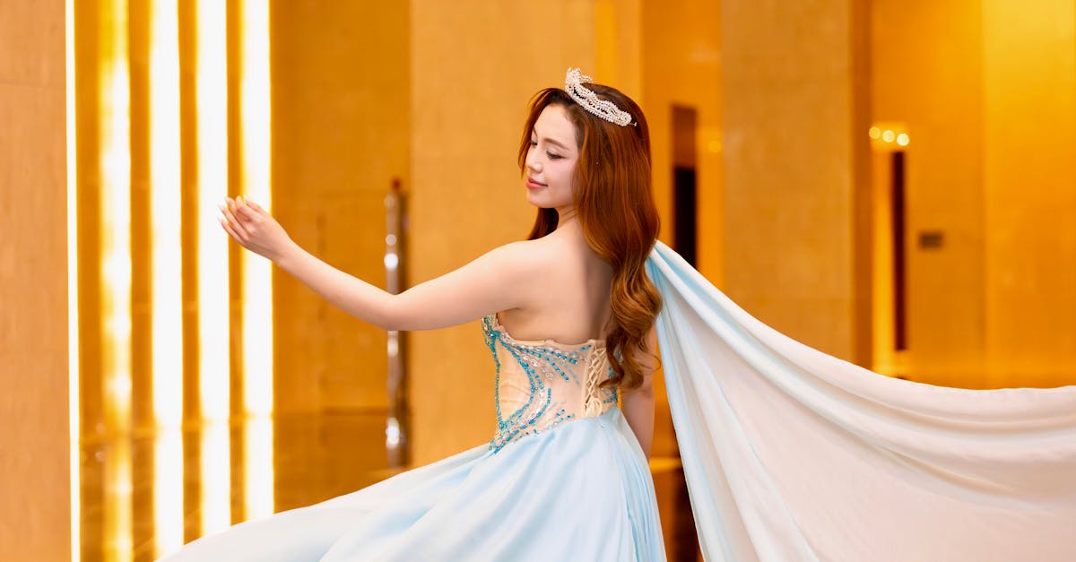 Photo by Hồng Quang Official A young woman in a blue gown gracefully poses in an elegant indoor setting.