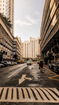 City street view with tall buildings, cars, and a cyclist on a sunny day.