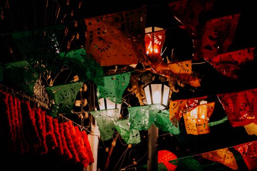 Colorful papel picado and lights at night creating a festive atmosphere.
