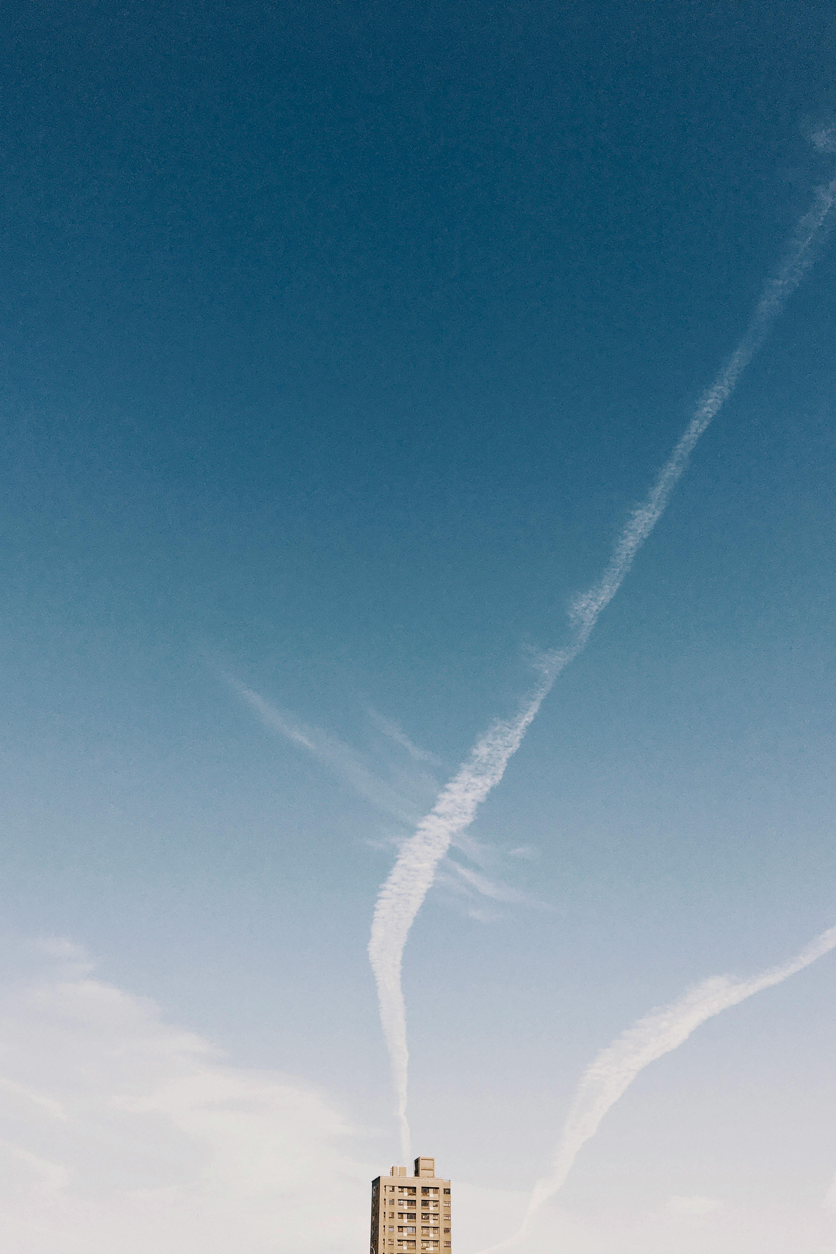 一座孤独的建筑矗立在清澈的蓝天下，背景是天空与轨迹