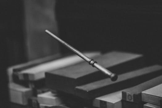 一张艺术黑白照片中，一根魔杖悬浮在木箱上，景深效果显著