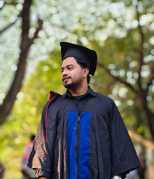 Free A young man wearing graduation attire stands confidently outdoors. Stock Photo
