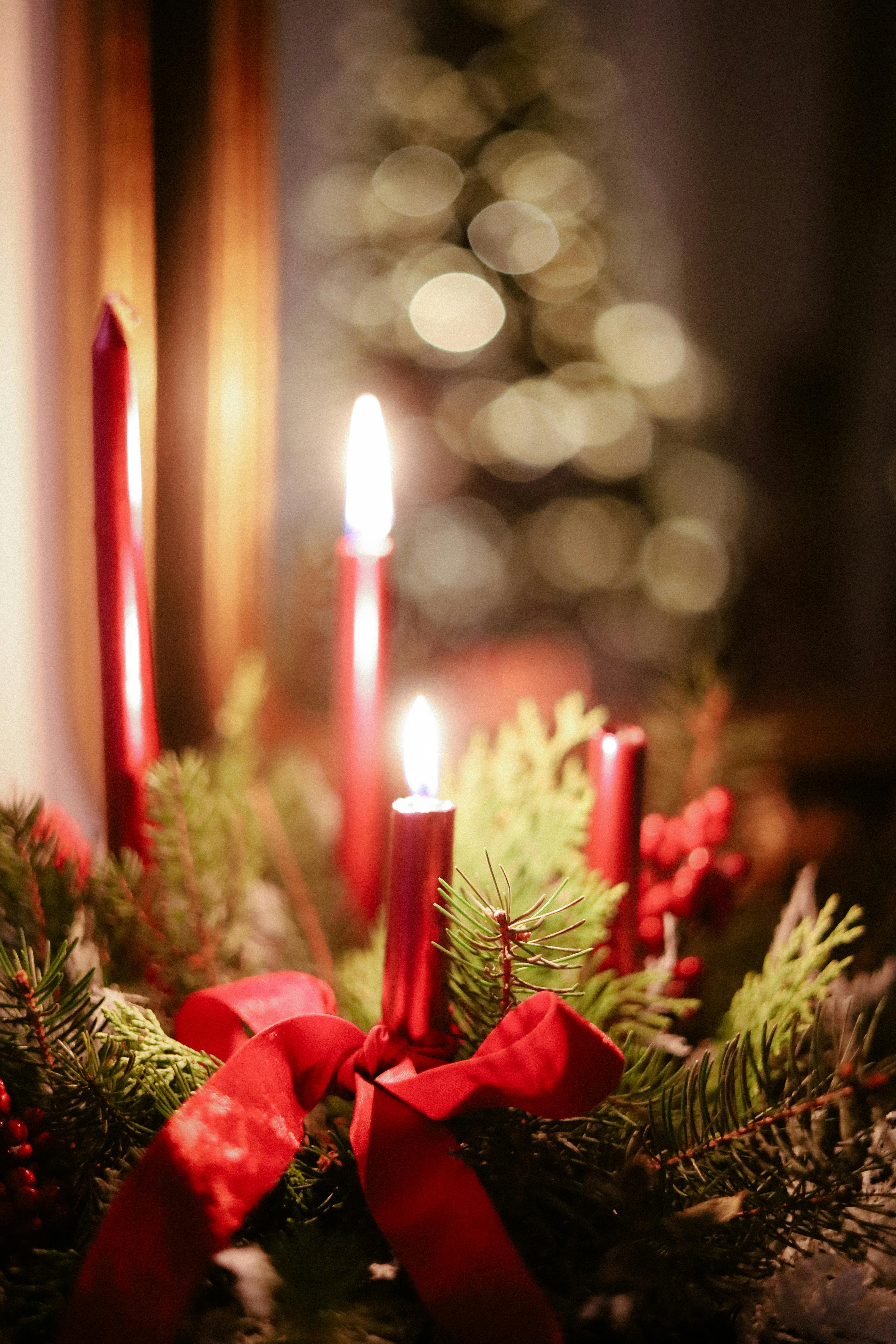 Red candles with greenery and ribbons create a warm Christmas ambiance.