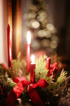 Red candles with greenery and ribbons create a warm Christmas ambiance.