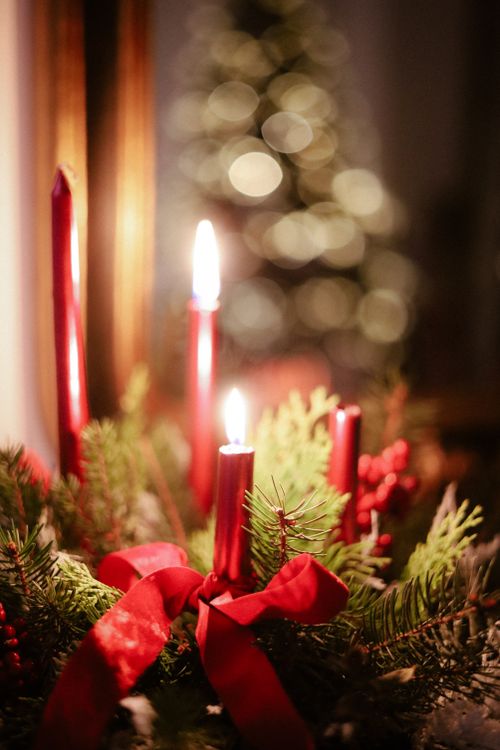 Free Red candles with greenery and ribbons create a warm Christmas ambiance. Stock Photo