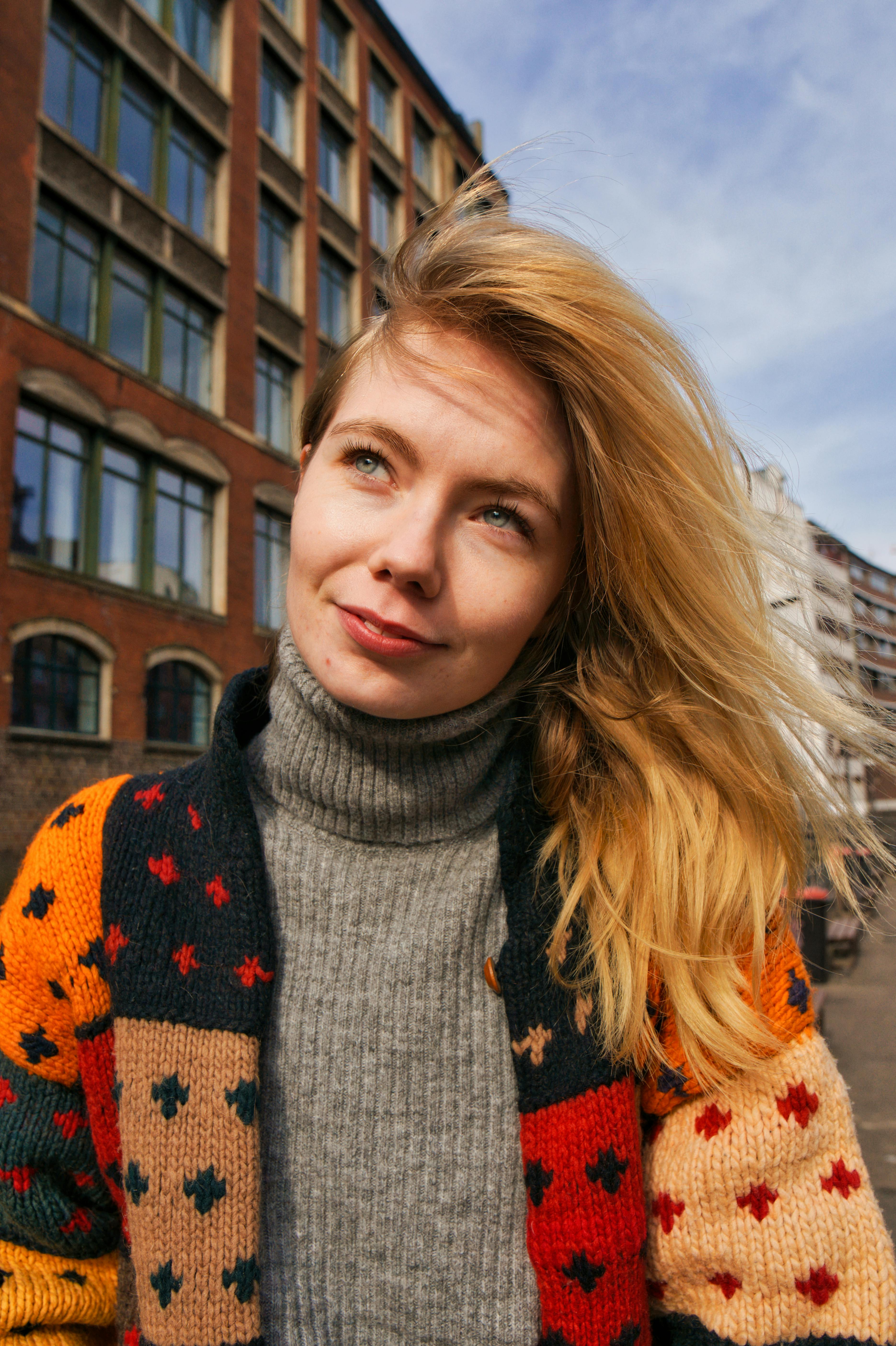 Smiling woman outdoors in Hamburg wearing a colorful sweater, embodying a vibrant and positive mood.