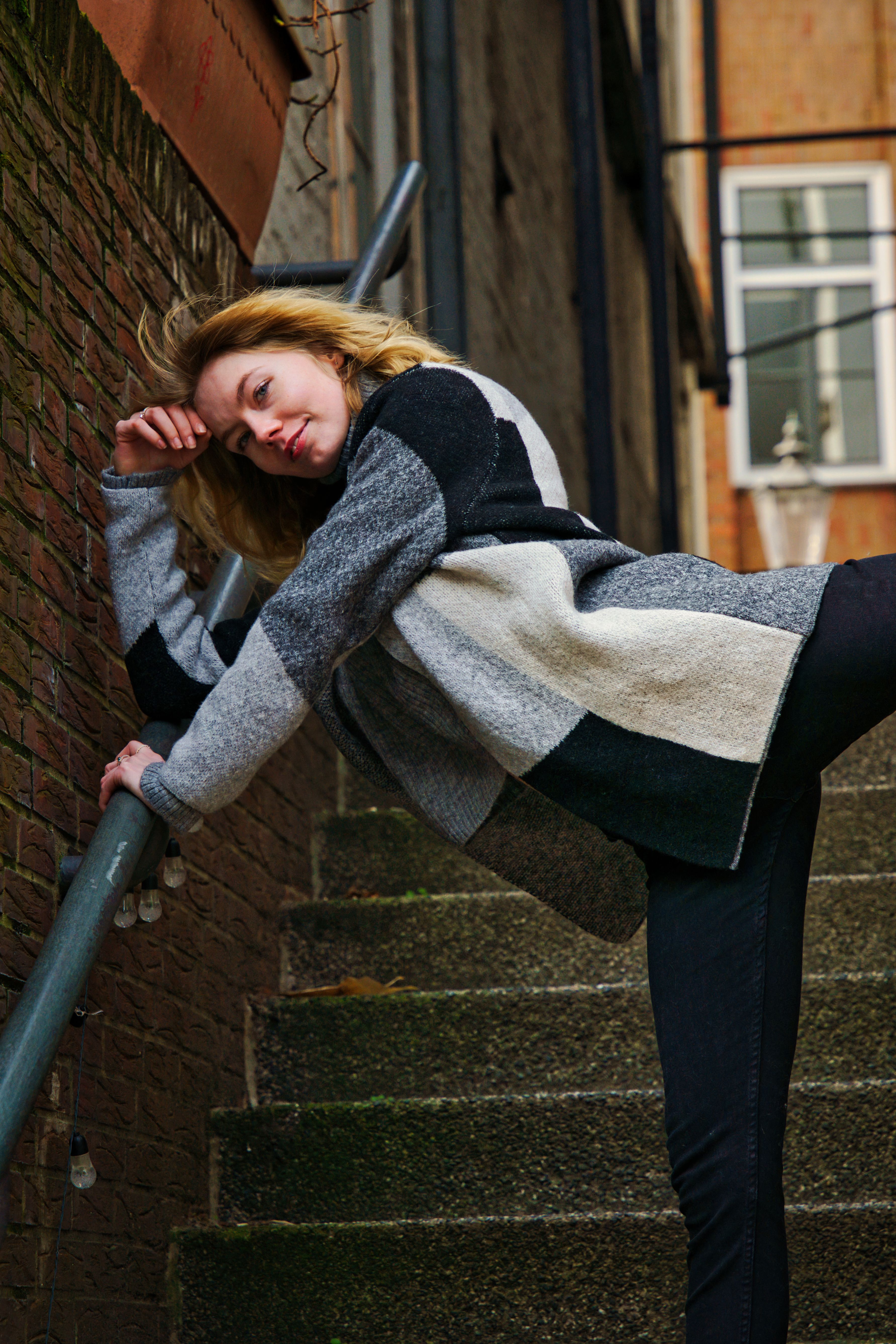 A woman poses creatively on stairs in a Hamburg street, showcasing a casual urban style.