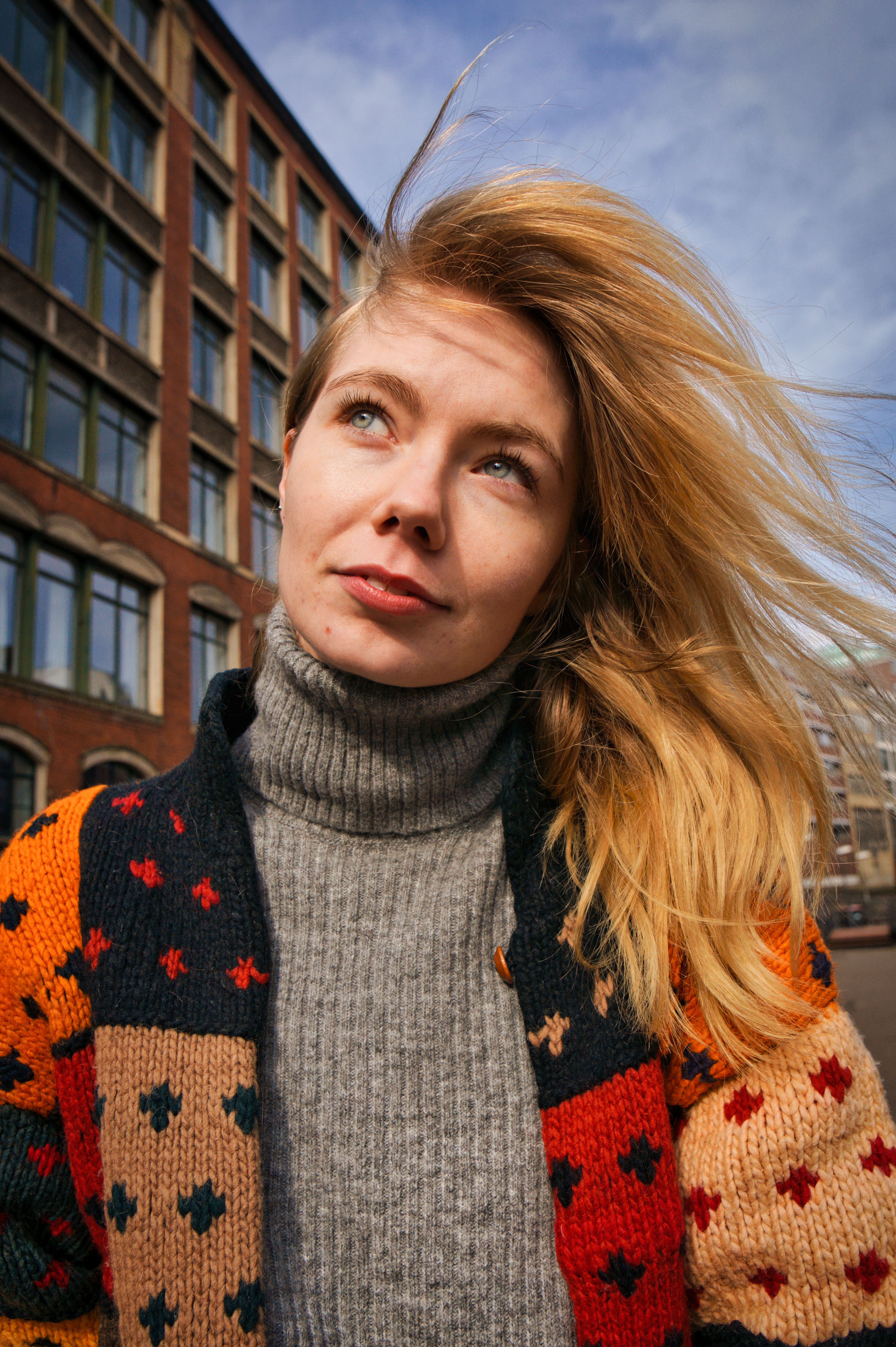 Portrait of a woman in a colorful sweater, looking thoughtful on a sunny day in Hamburg.