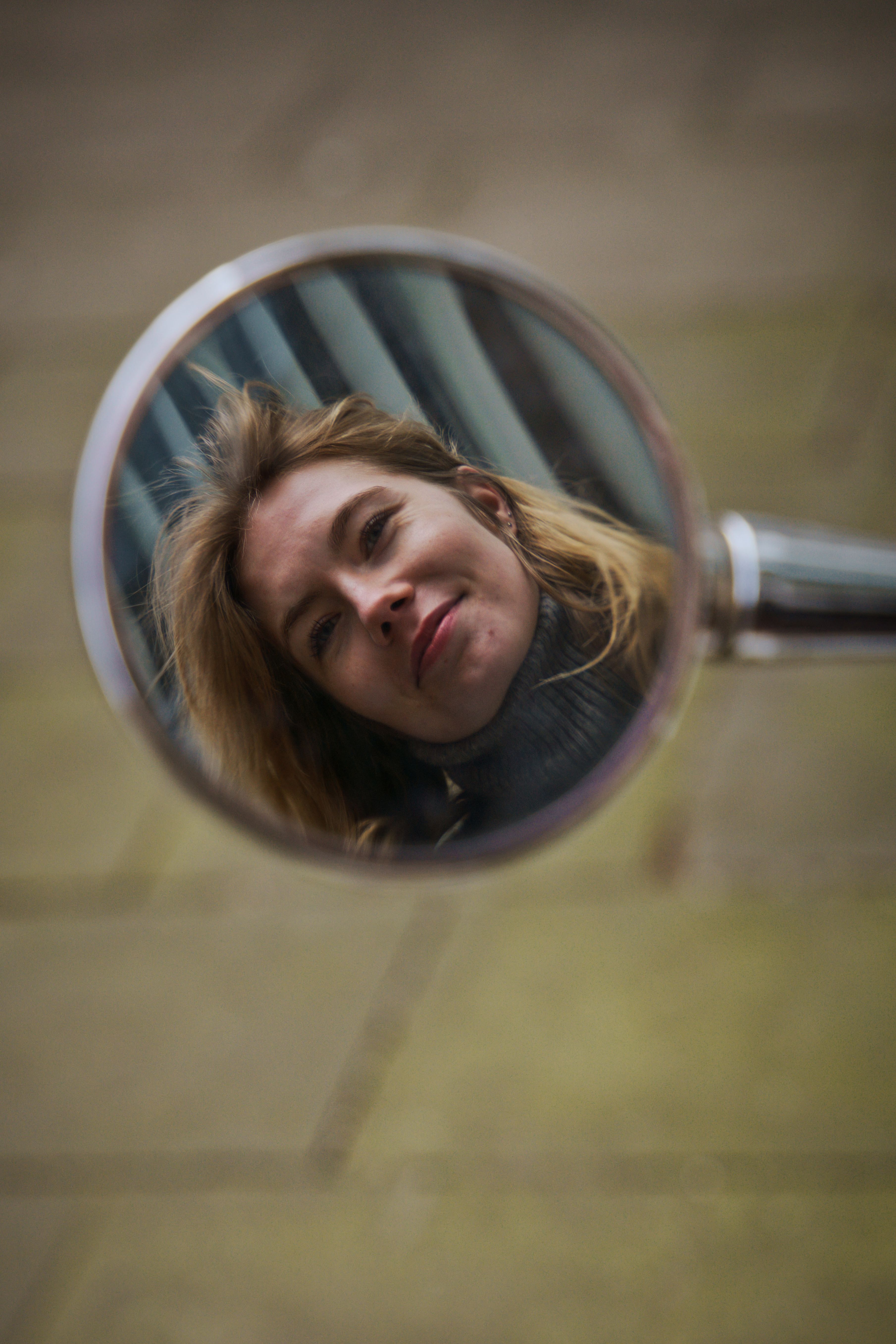 Artistic reflection of a woman in a scooter mirror, captured outdoors in Hamburg.