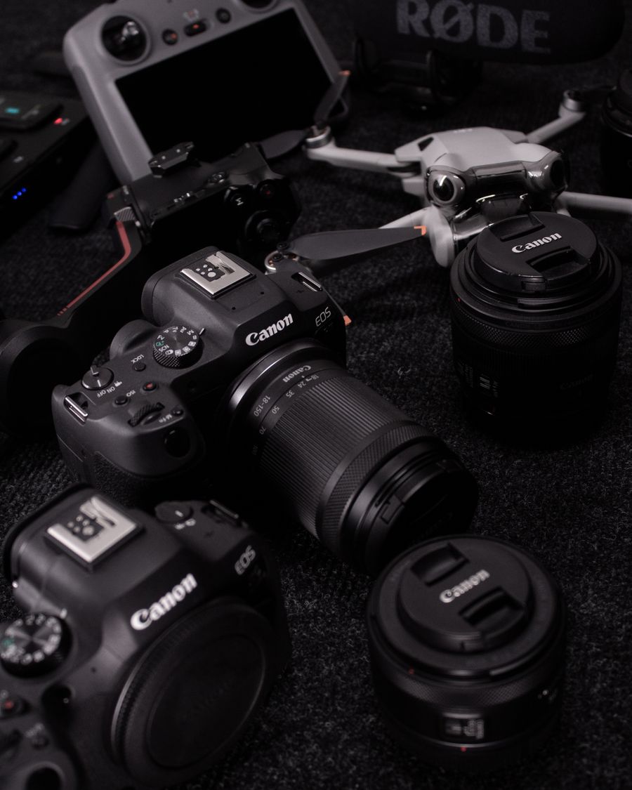 A range of professional cameras, lenses and drones laid out together in a workshop