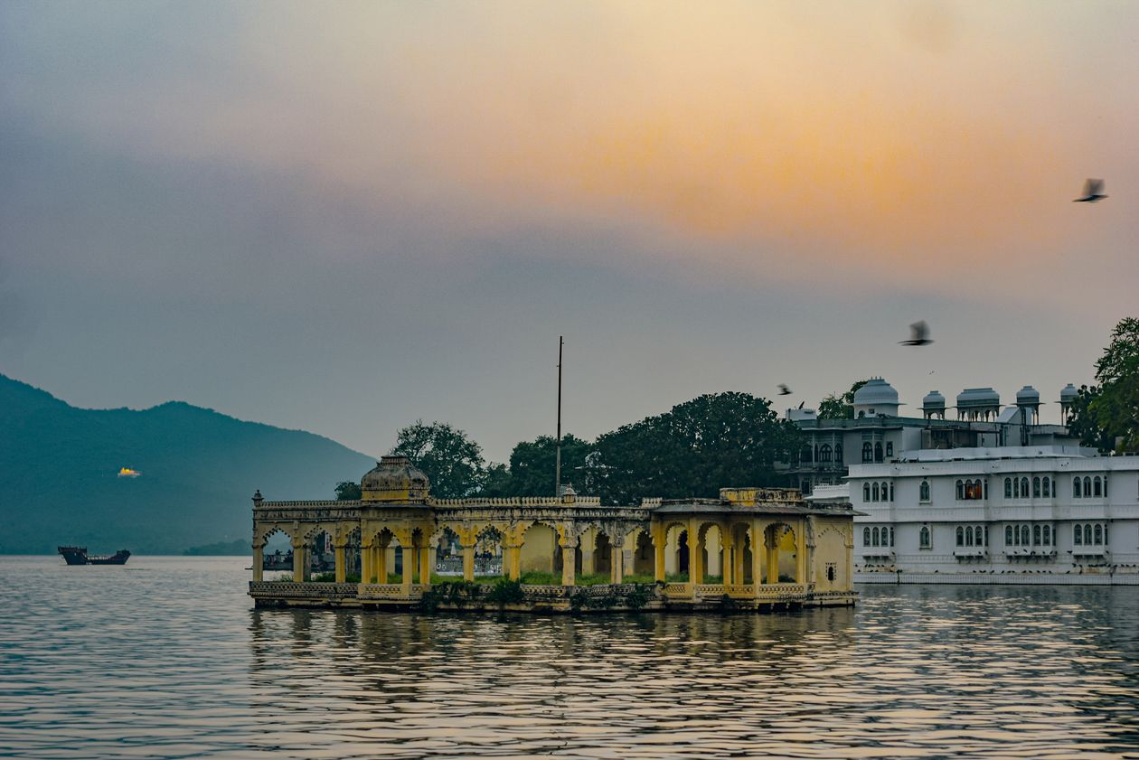 Lake Palace on Lake Pichola in Udaipur at sunset with birds in flight