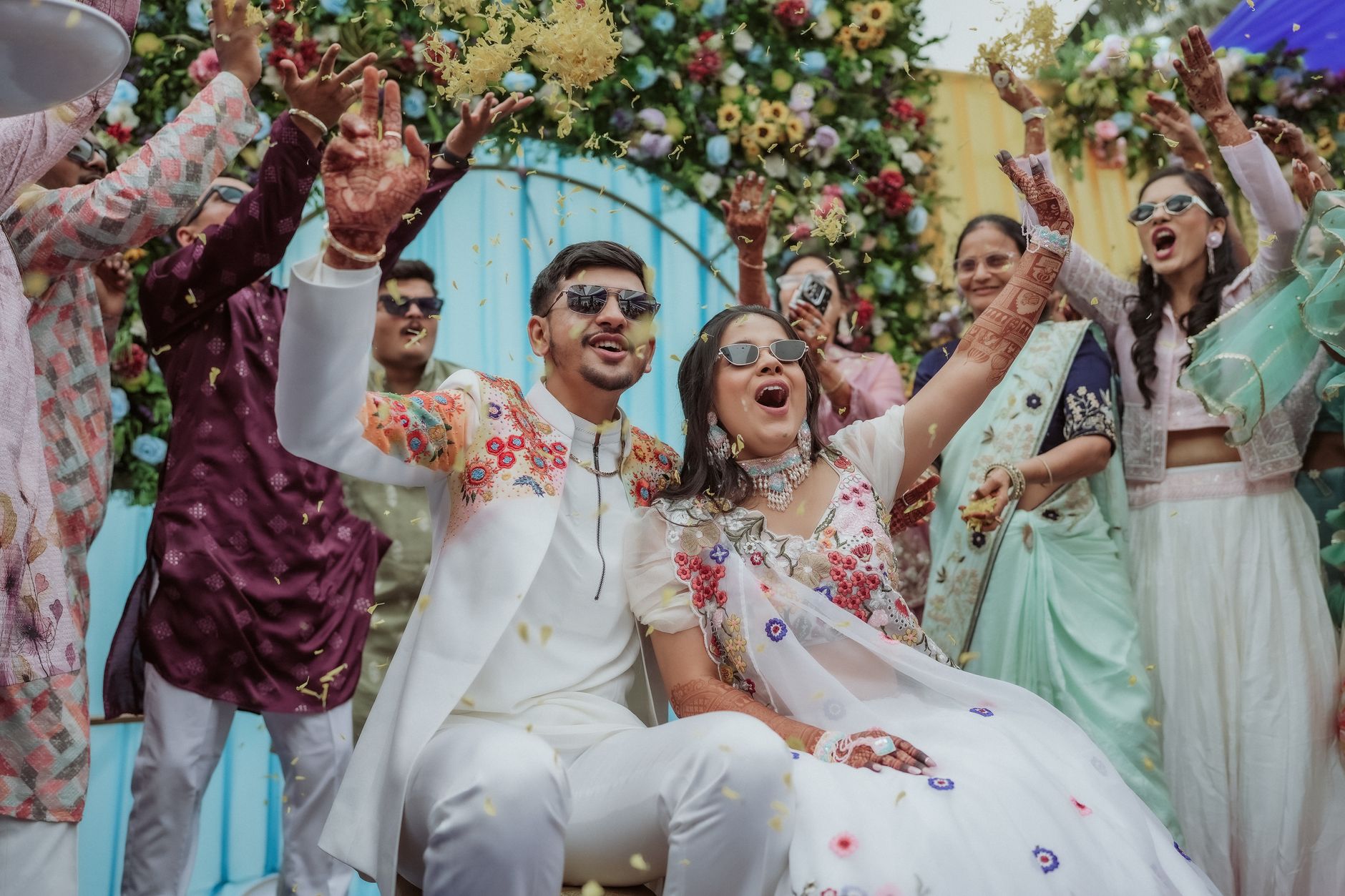 Vibrant Indian wedding scene with happy couple and guests celebrating with confetti.