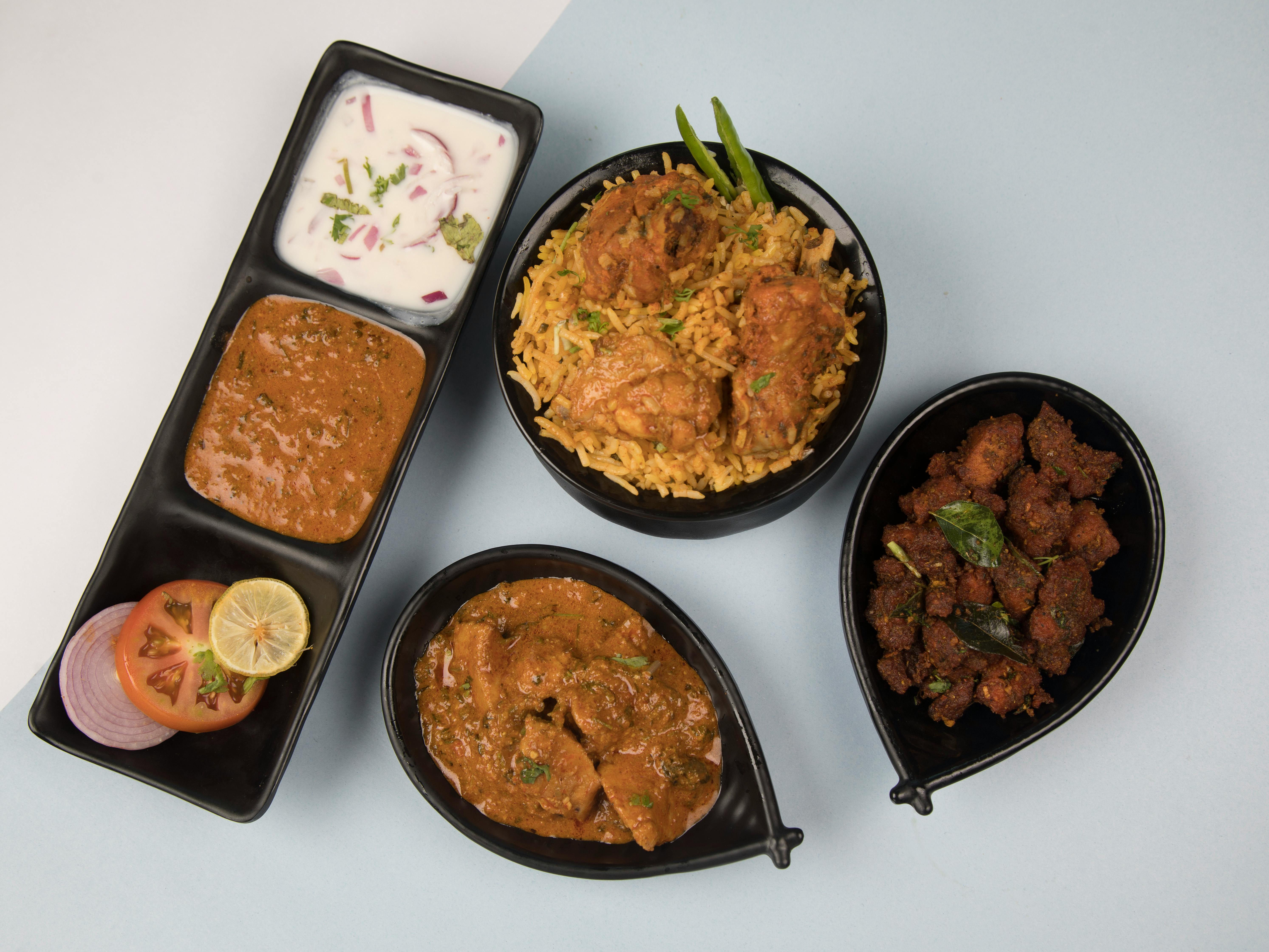 Overhead view of a traditional Indian meal with biryani, curry, and side dishes.