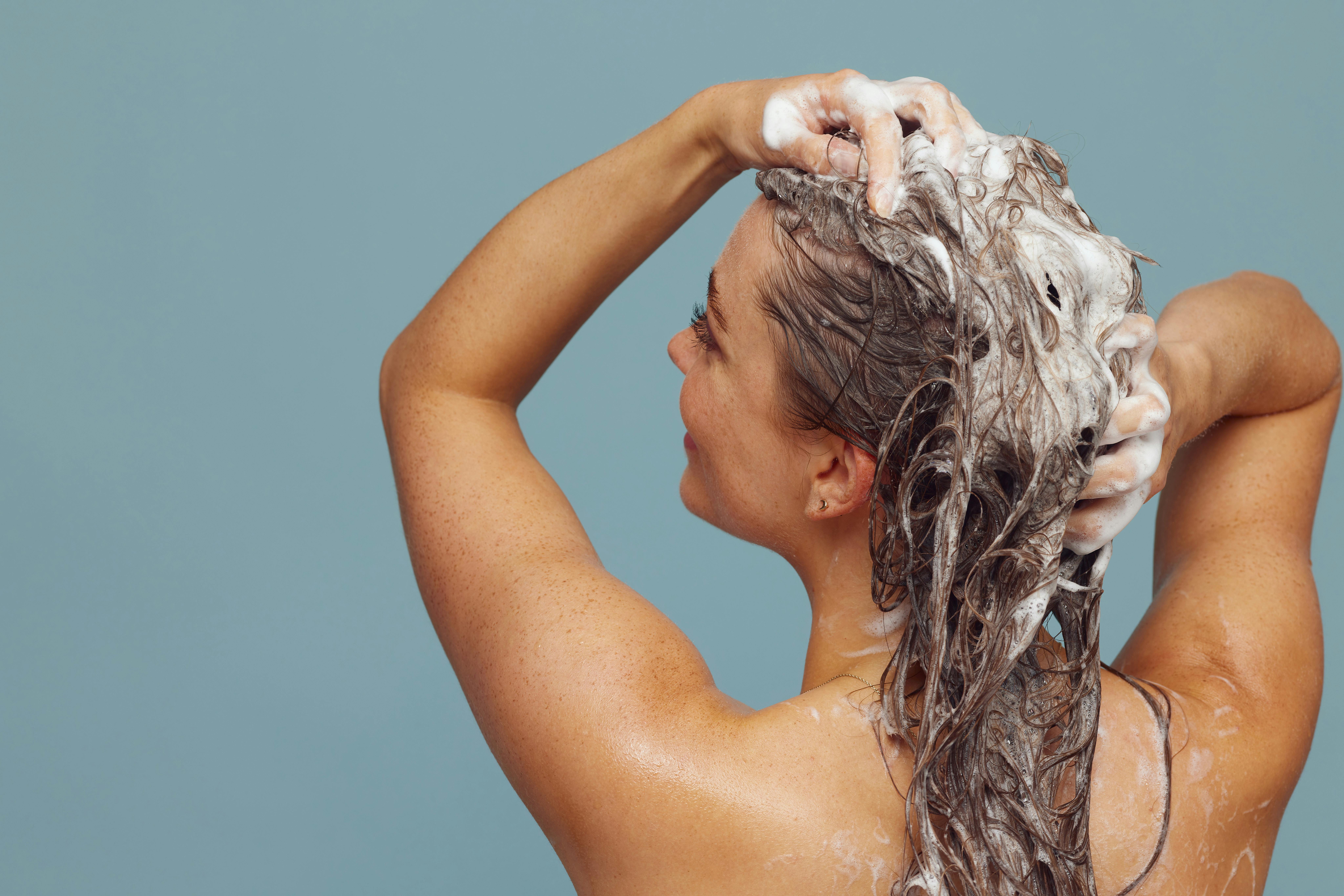 Femme se lavant les cheveux sous la douche