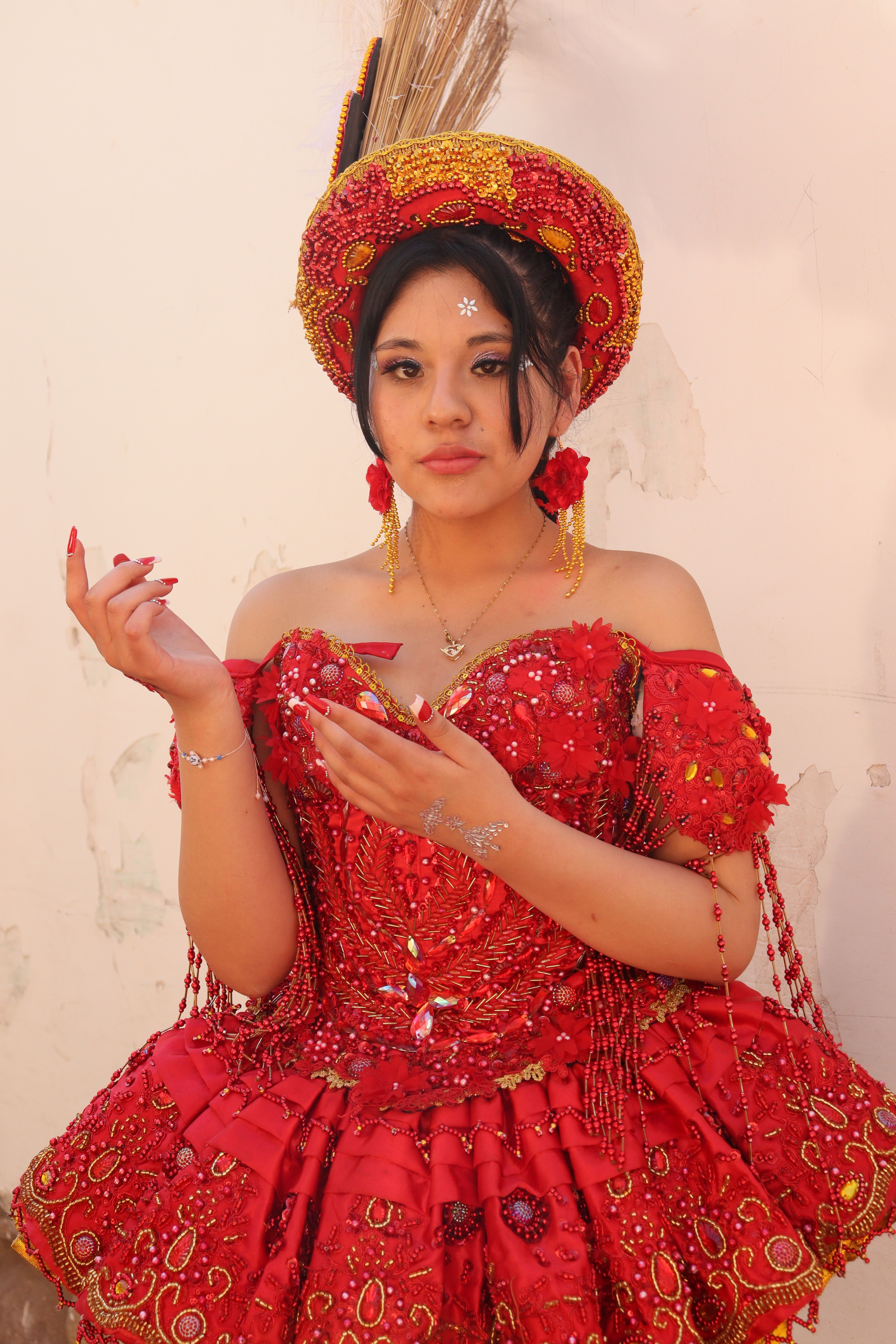 Portrait of a young woman dressed in vibrant traditional red attire with intricate designs.