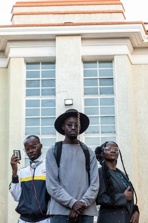 Free Three stylish young adults pose confidently against a modern architectural backdrop. Stock Photo