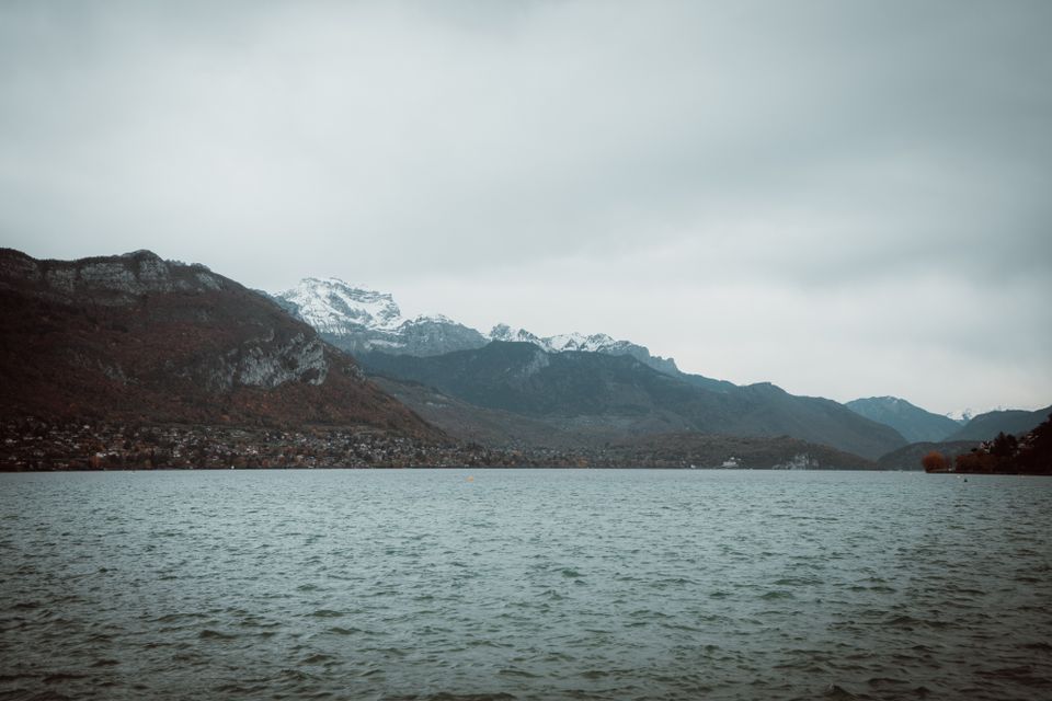 Tranquil view of Lake Annecy with snow-capped Alps mountains in autumn.