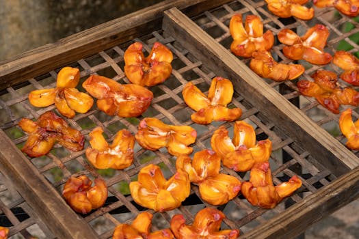 Freshly dried persimmons arranged on wooden racks outdoors, showcasing vibrant colors.