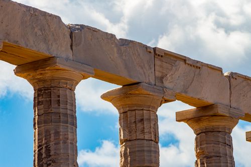Free Close-up of ancient Greek stone columns under a bright blue sky, showcasing historical architecture. Stock Photo