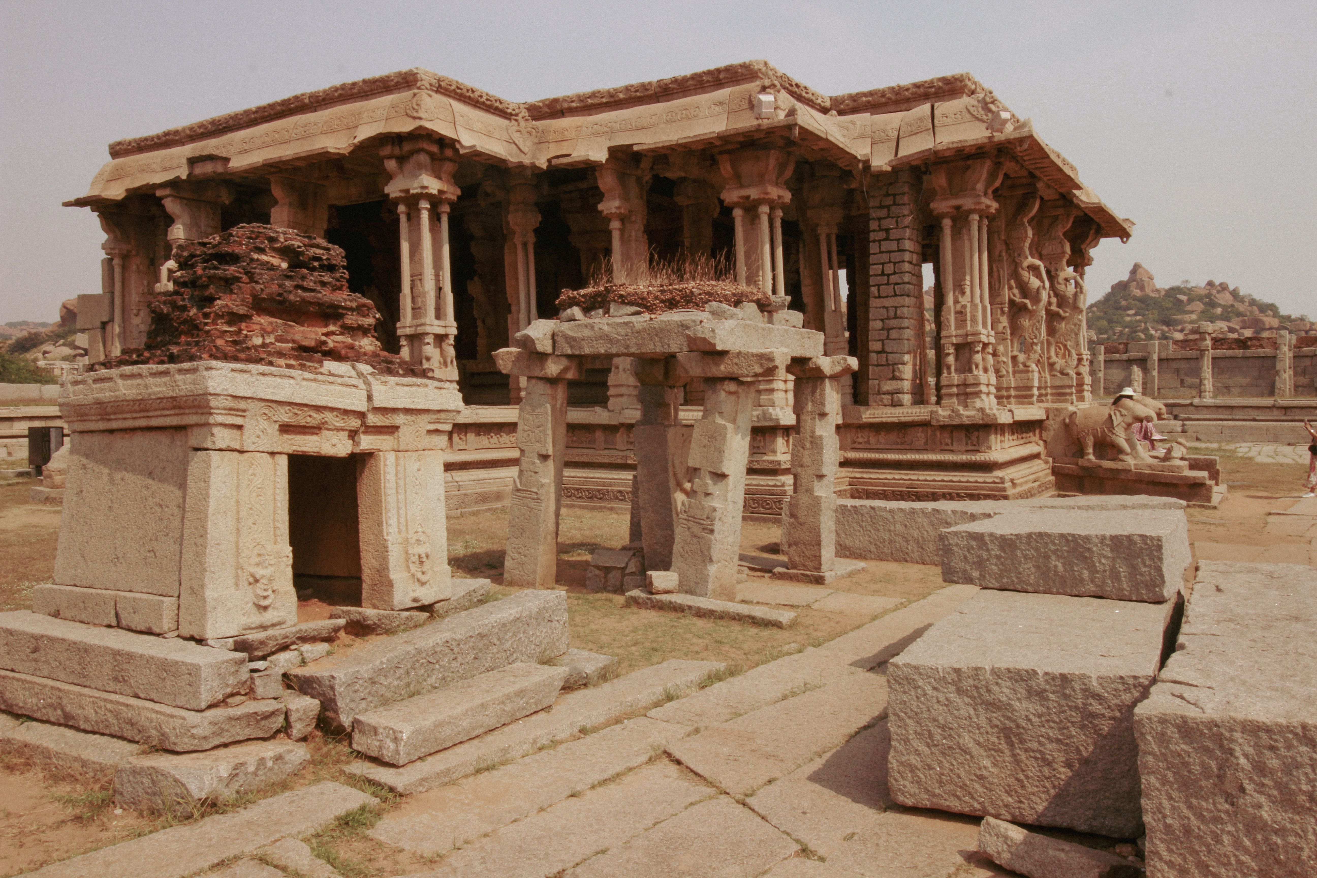 Explore the ancient architecture of a stone temple in Hampi, Karnataka, showcasing intricate carvings and historic ruins.