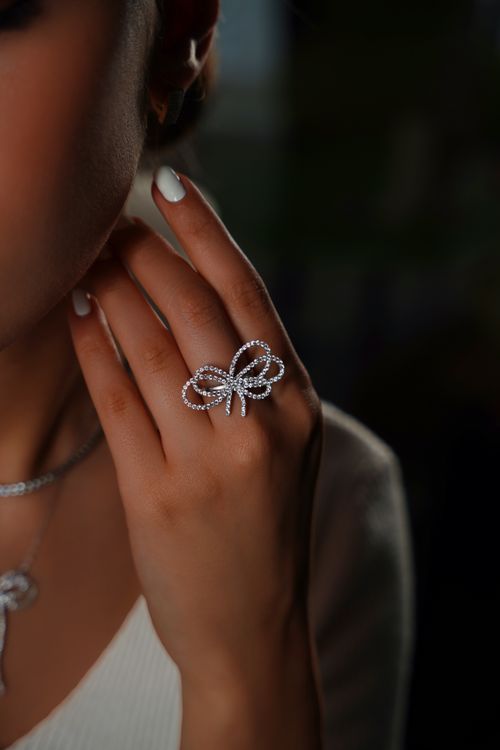 Free Elegant close-up of a diamond bow ring on a woman's hand showcasing luxury jewelry. Stock Photo
