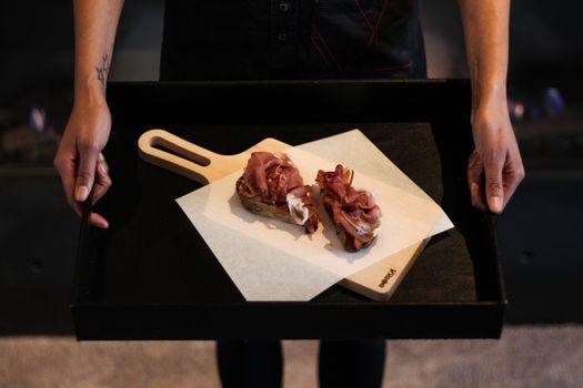 Hands presenting gourmet charcuterie on a tray, perfect for food and lifestyle concepts.
