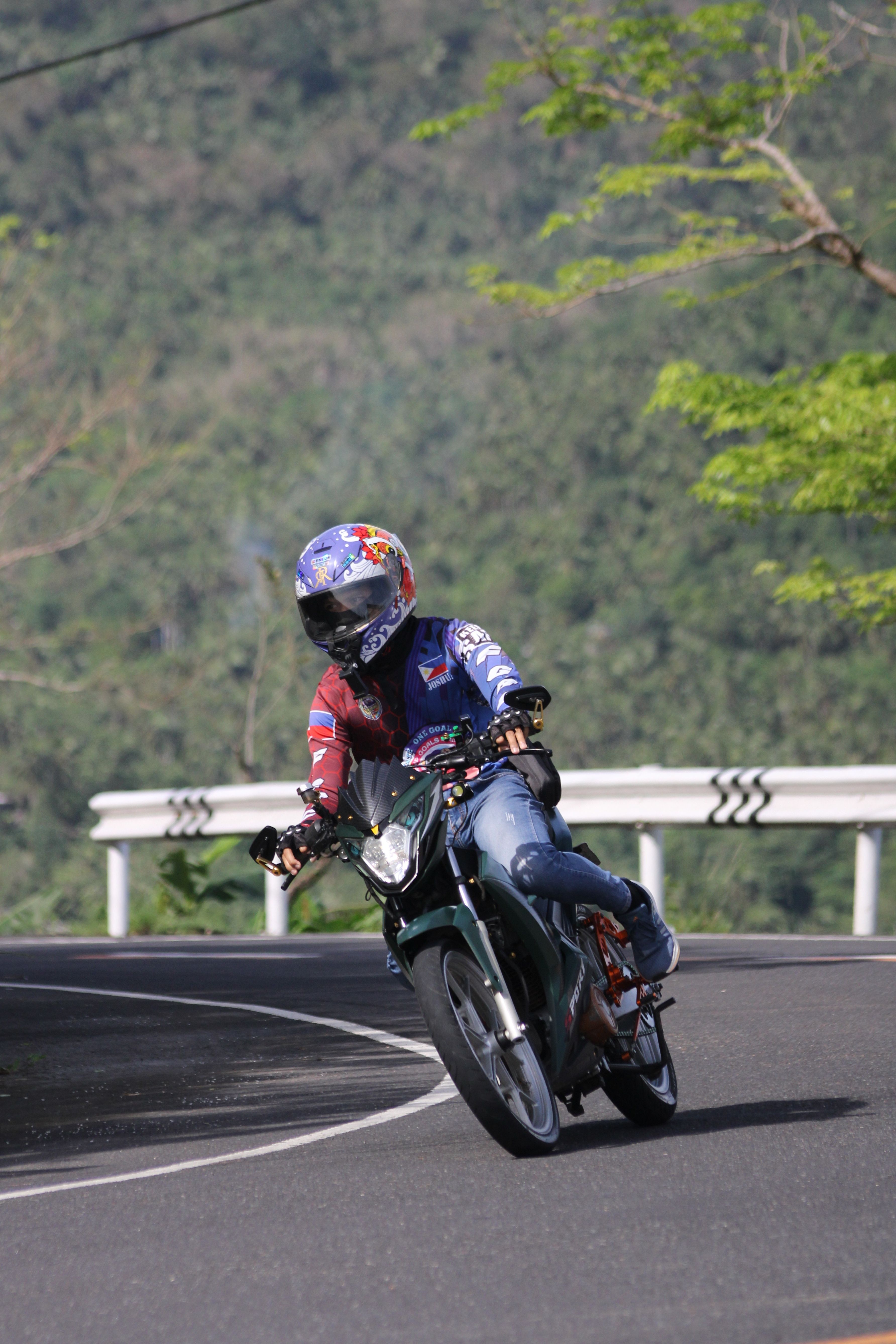 A motorcyclist expertly leans into a curve on a scenic mountain road, showcasing thrilling speed and agility.