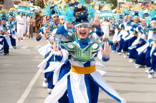 Energetic participants in traditional costumes dance at a lively street festival parade.