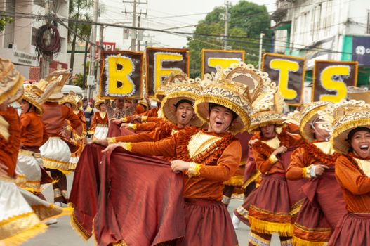 Vibrant street parade featuring dancers in traditional costumes with ornate hats during a cultural festival.