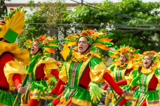 Dancers in bright costumes perform energetically at a cultural street parade, embracing vibrant traditions.