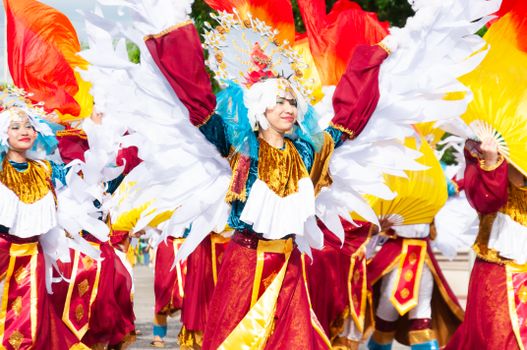 Vibrant festival parade with performers in colorful costumes and feathered headdresses.