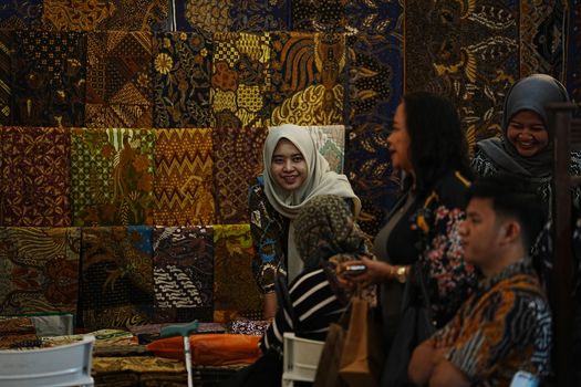 A lively indoor scene showcasing traditional Batik fabrics in Bandung, Indonesia. - Fotografer Sidoarjo