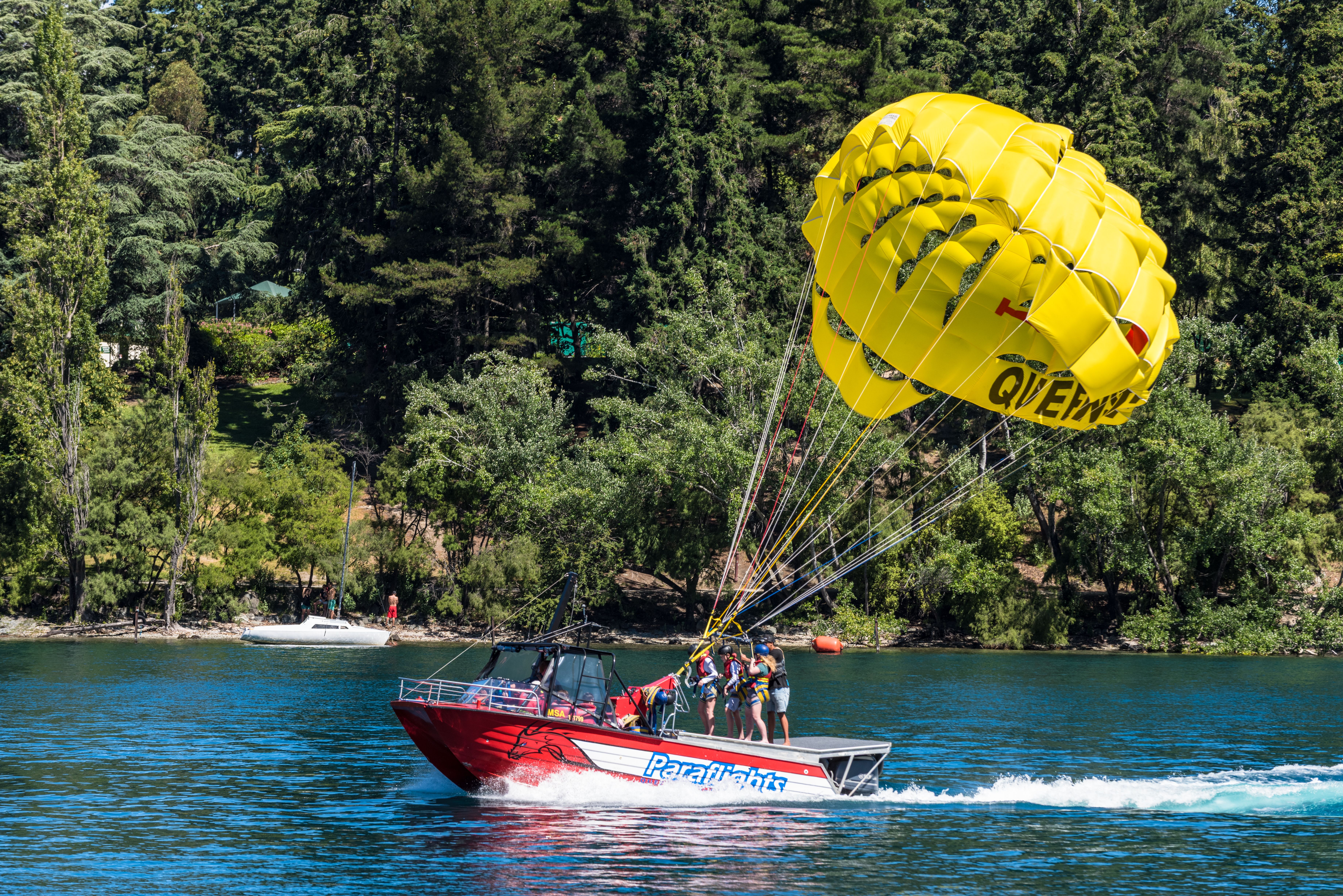A thrilling parasailing experience above a picturesque lake surrounded by lush forest.