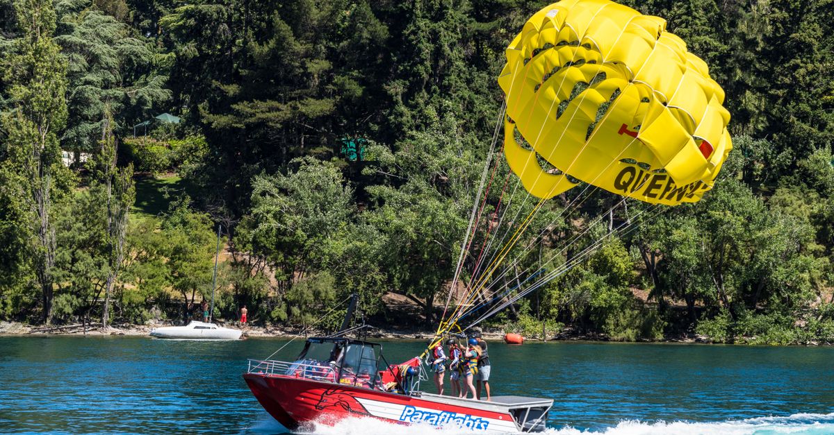 A thrilling parasailing experience above a picturesque lake surrounded by lush forest.