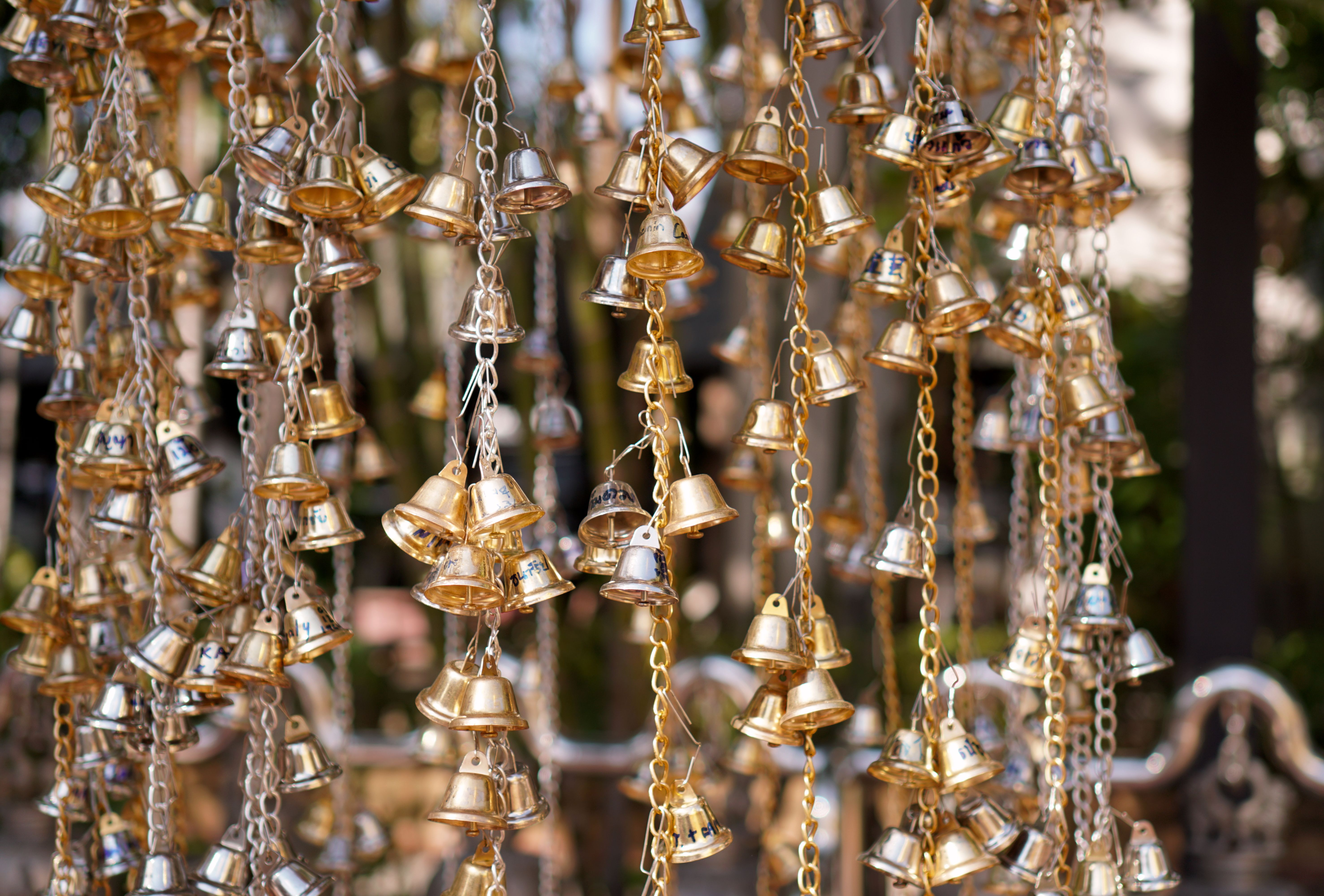 Close-up of golden temple bells at a Buddhist temple in Chiang Mai, Thailand, showcasing cultural heritage.