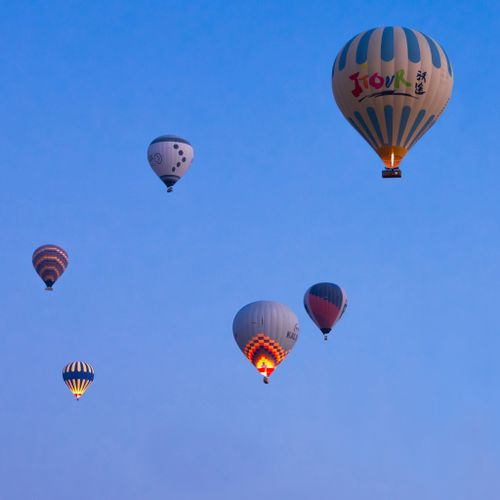 Free Multiple hot air balloons float against a clear blue sky at sunrise, creating a vibrant scene. Stock Photo
