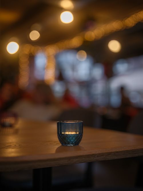 Free Warm candlelit setting in a cozy cafe with festive lights, creating a relaxing atmosphere. Stock Photo