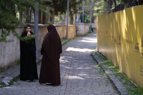 Free Two women in traditional attire walking along a cobblestone street in Istanbul. Stock Photo