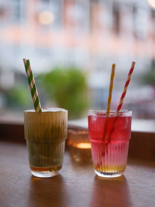 Free Vibrant drinks with striped straws on a wooden table, creating a cozy indoor ambiance. Stock Photo