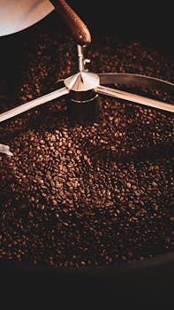 Photo by Berkan Can A close-up view of freshly roasted coffee beans in a coffee roaster with warm lighting.