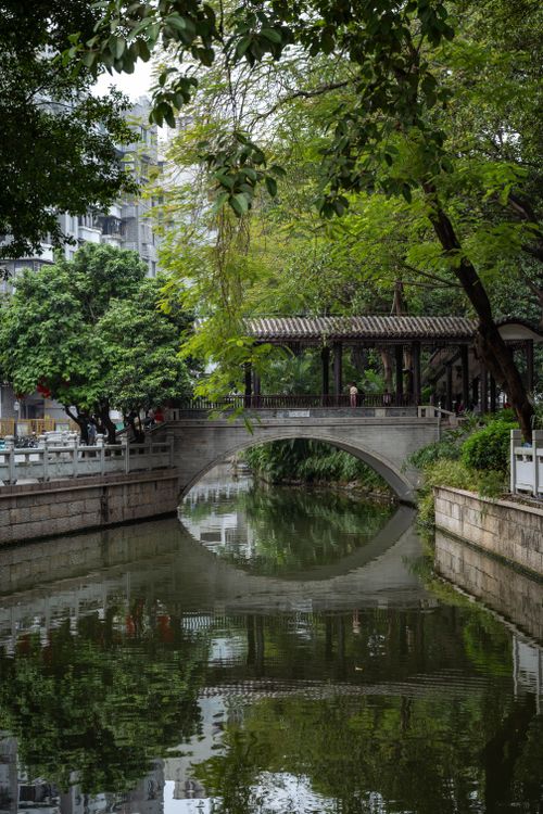 Free Calm scene of a stone bridge over a canal in Guangzhou, China, surrounded by lush greenery. Stock Photo