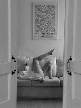 Monochrome living room with artistic leg pose on sofa, elegant décor.