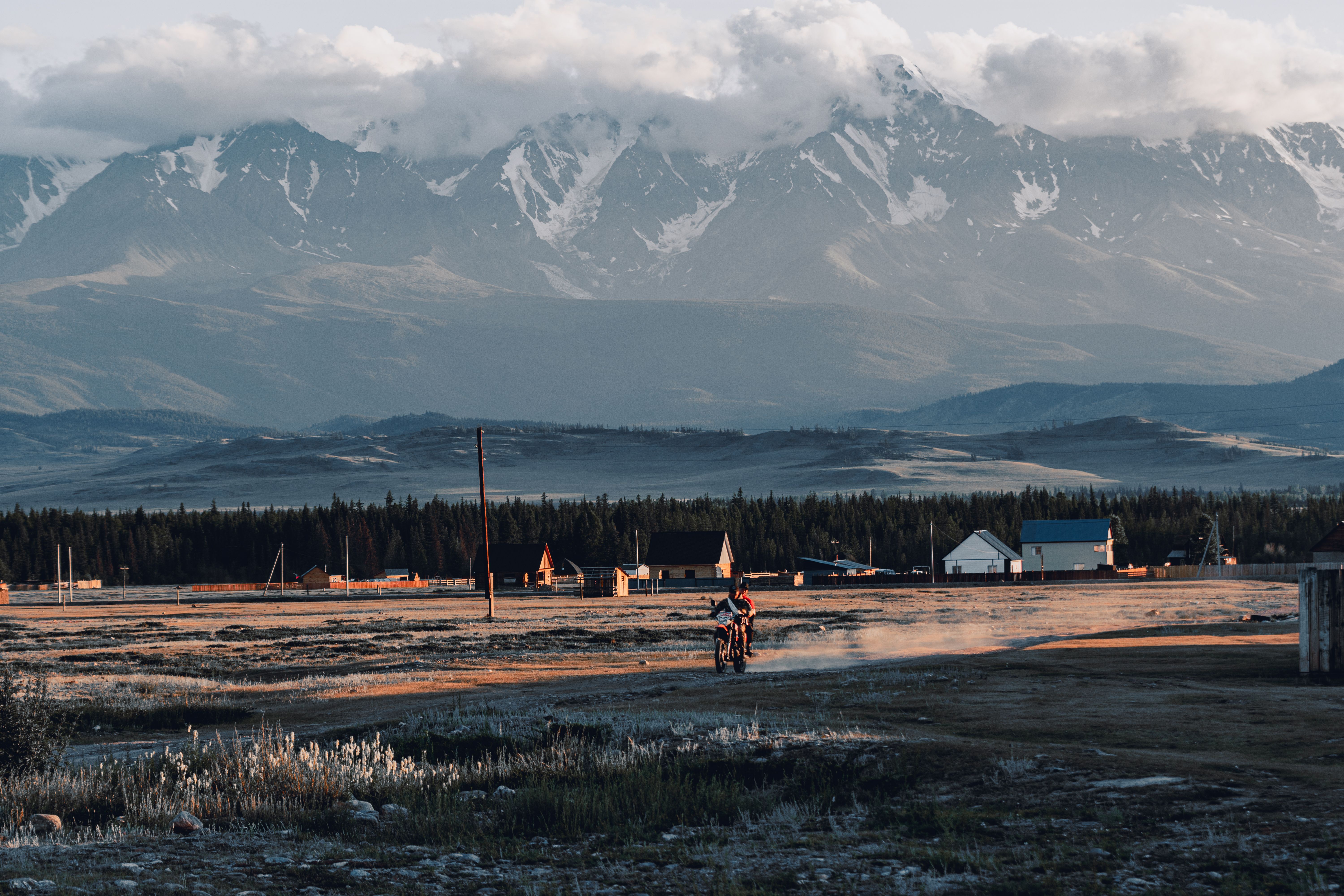 Dramatic view of a rider in Kurai, Russia, with snow-capped mountains at sunset.