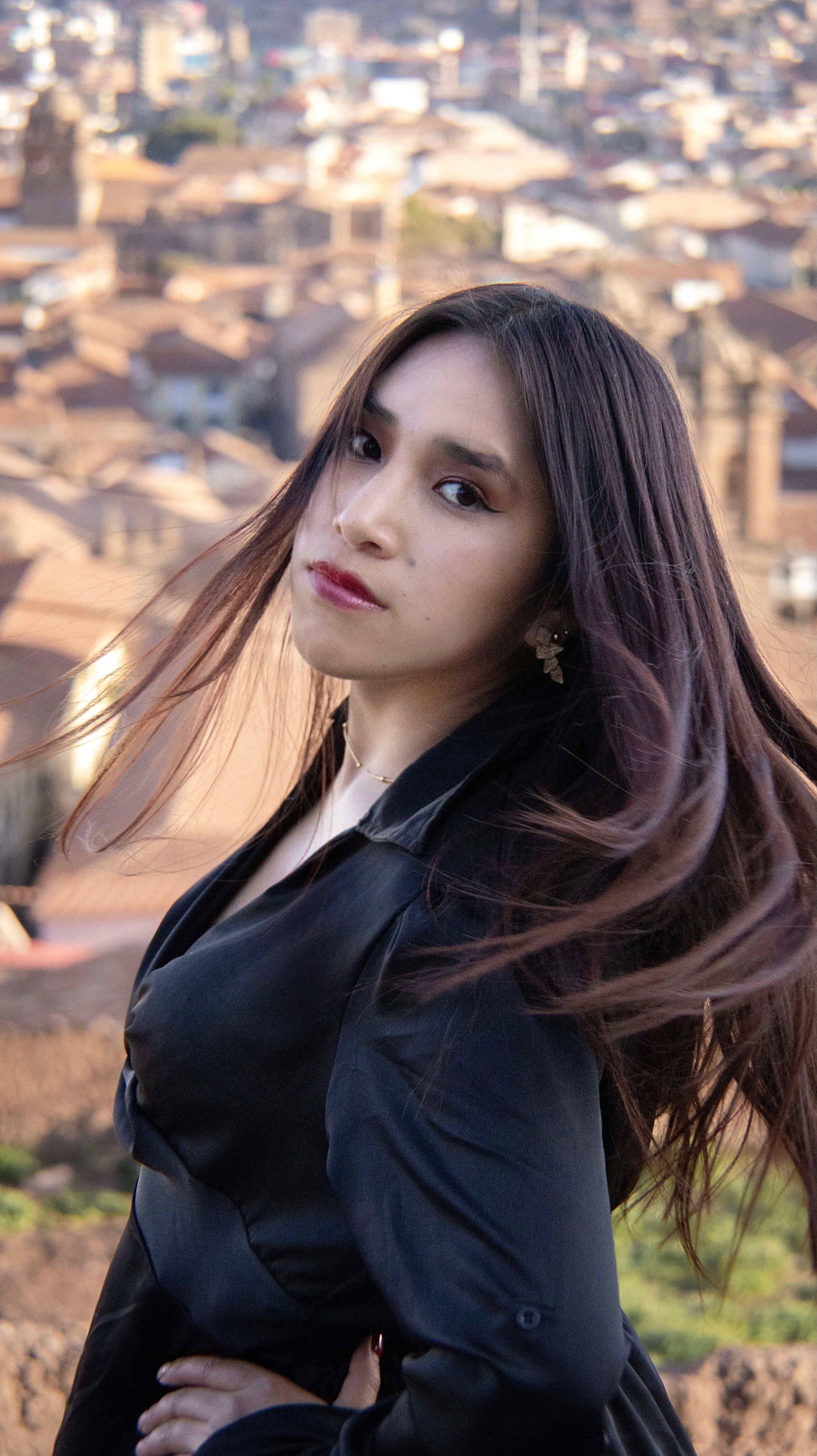 Portrait of a woman in black with a blurred cityscape background.