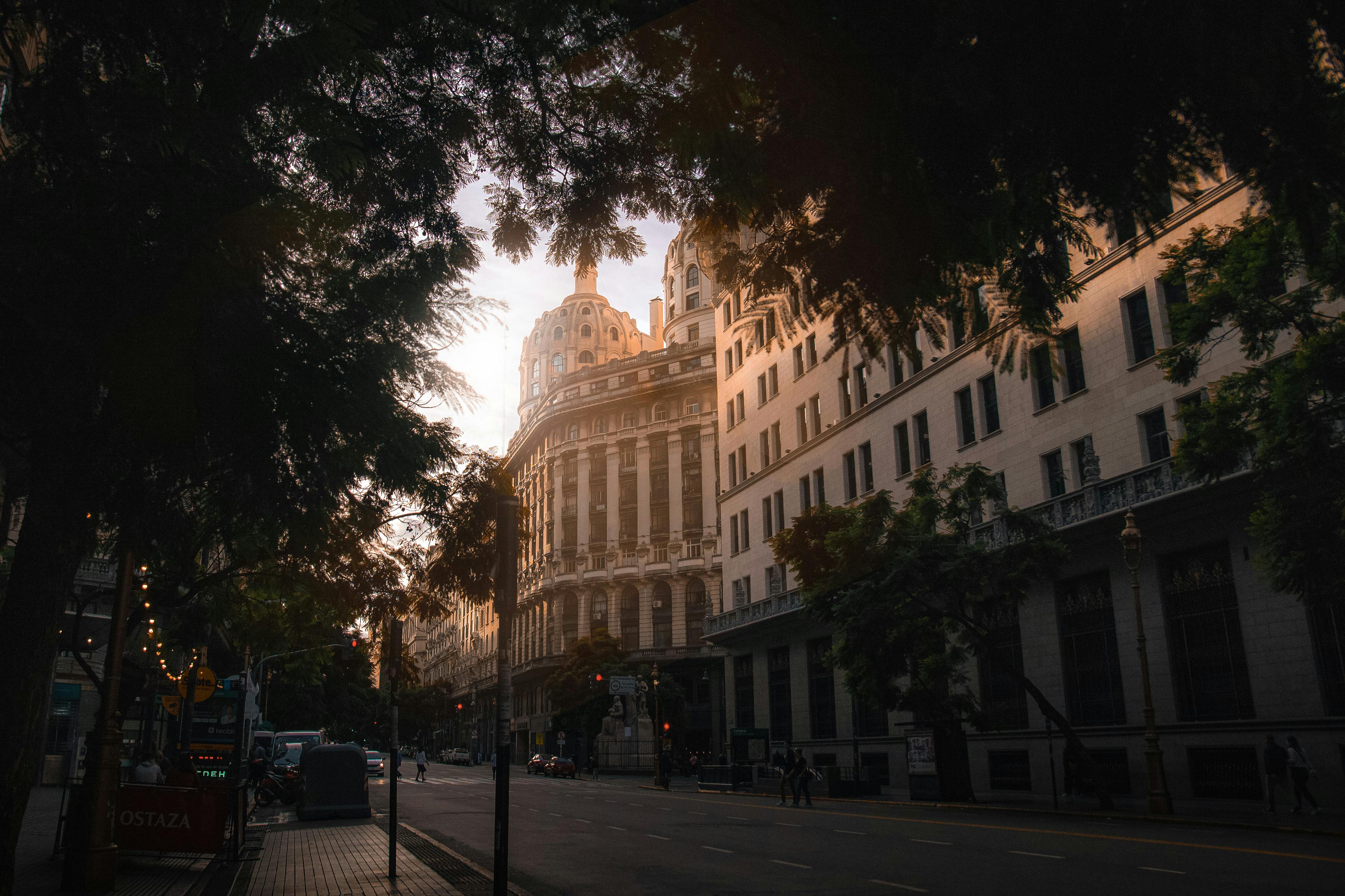 Classic urban architecture captured at sunset, highlighting ornate facade details amidst city trees.