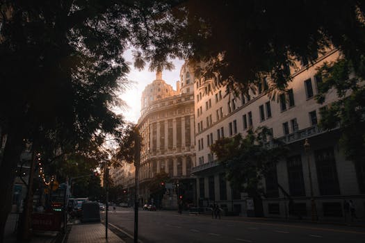 Classic urban architecture captured at sunset, highlighting ornate facade details amidst city trees.