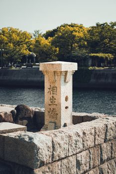 A scenic view of a historic stone marker by the river in Hiroshima, Japan.