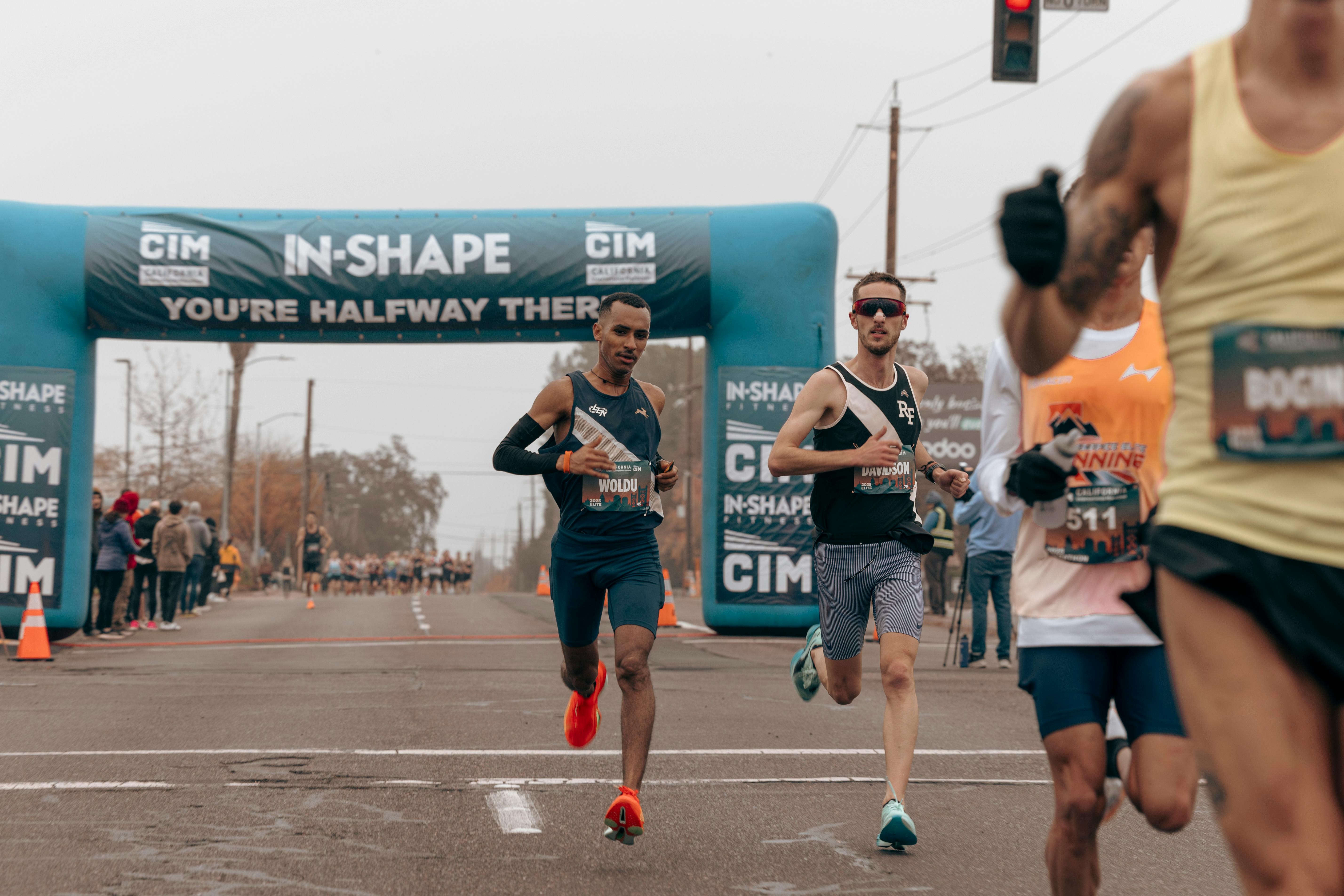 Marathon runners passing halfway mark at a public race on a city street.